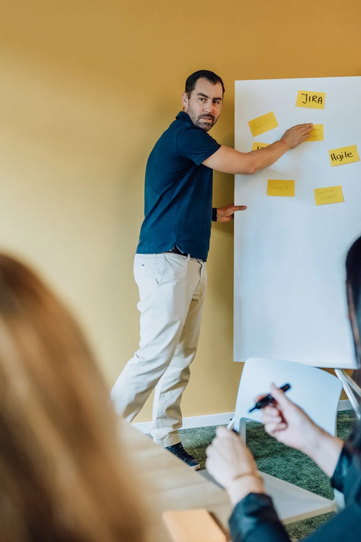 Man presenting ideas on a whiteboard with sticky notes in a meeting room.
